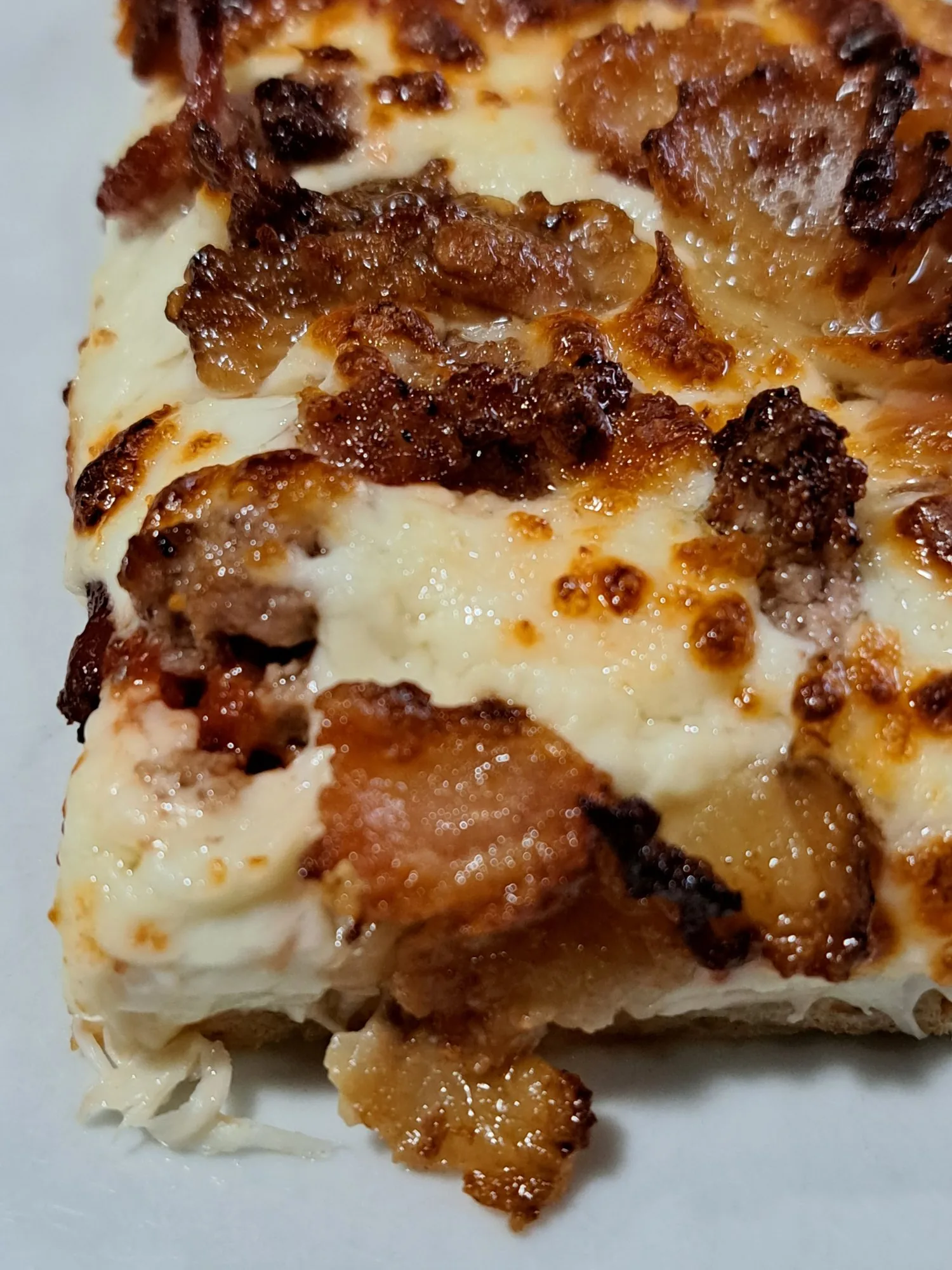 Close-up of real bacon and blistered cheese on a pizza