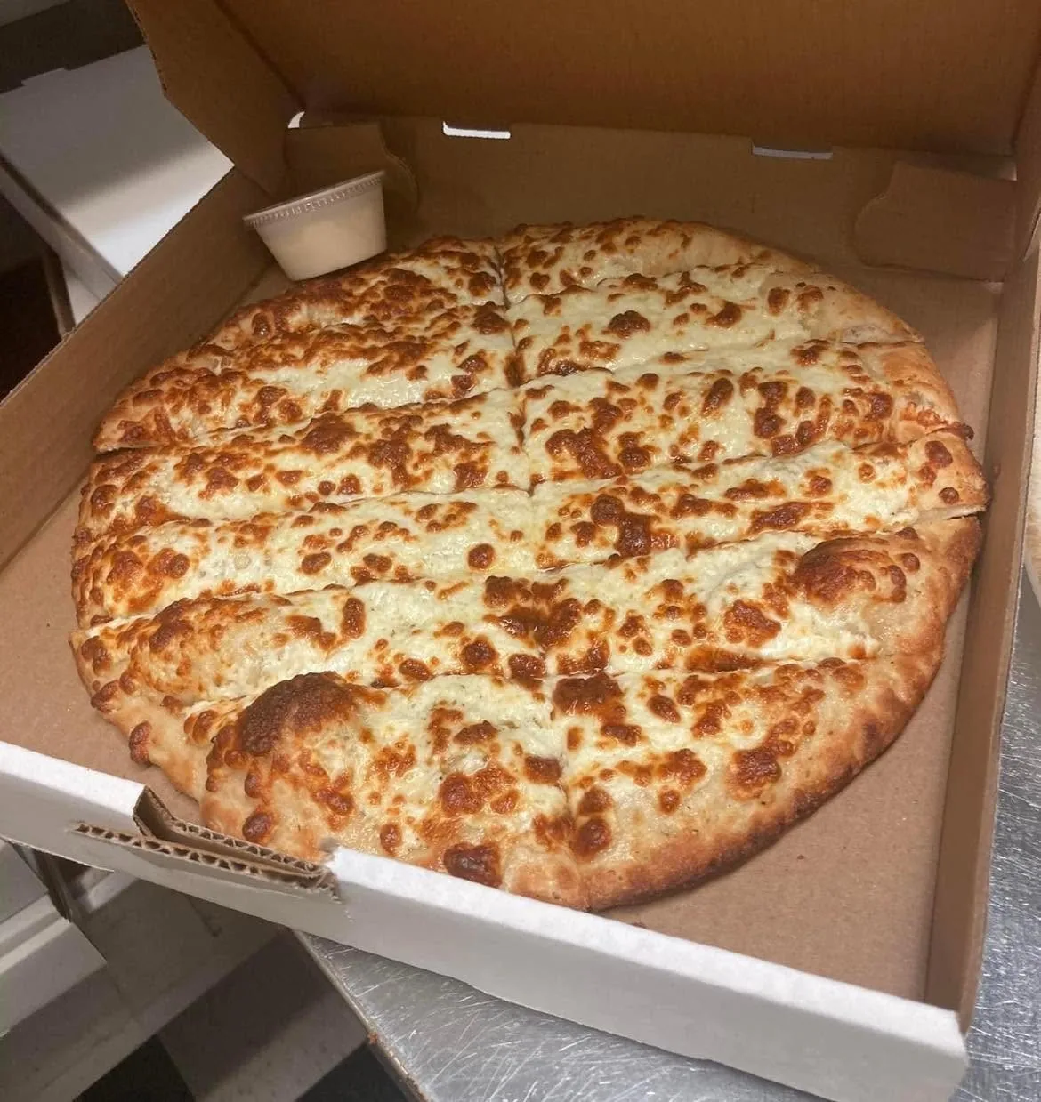 Garlic fingers in the box with a cup of homemade donair sauce