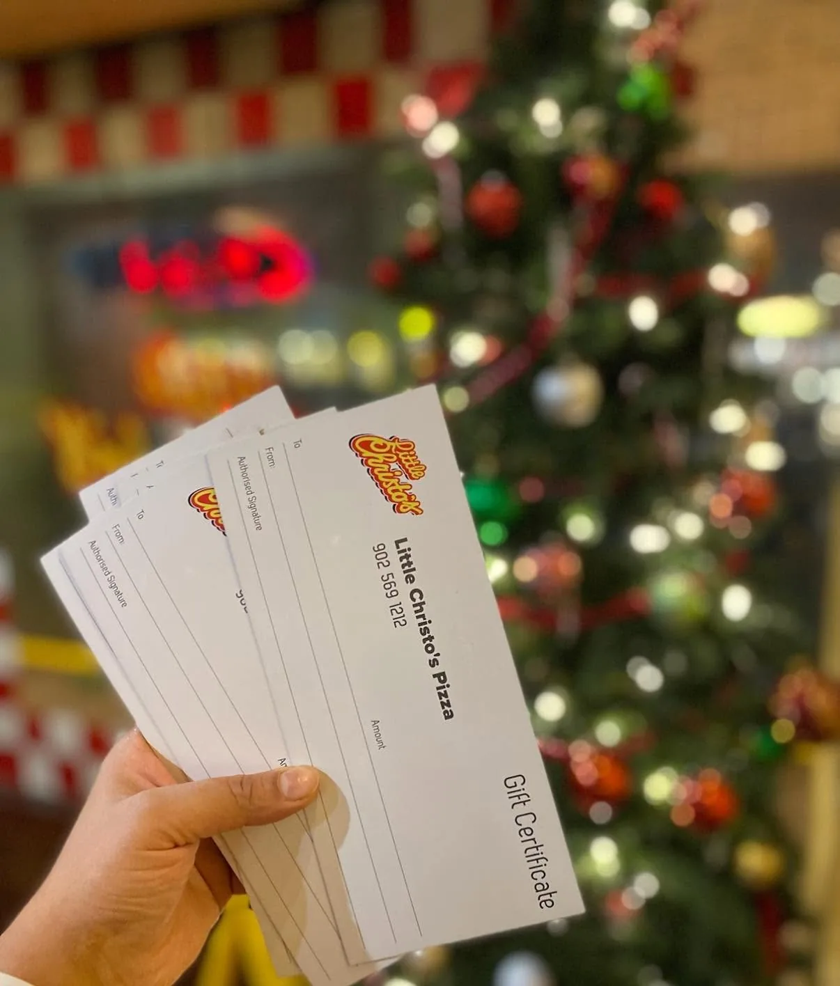 A hand holding Little Christo's gift certificates