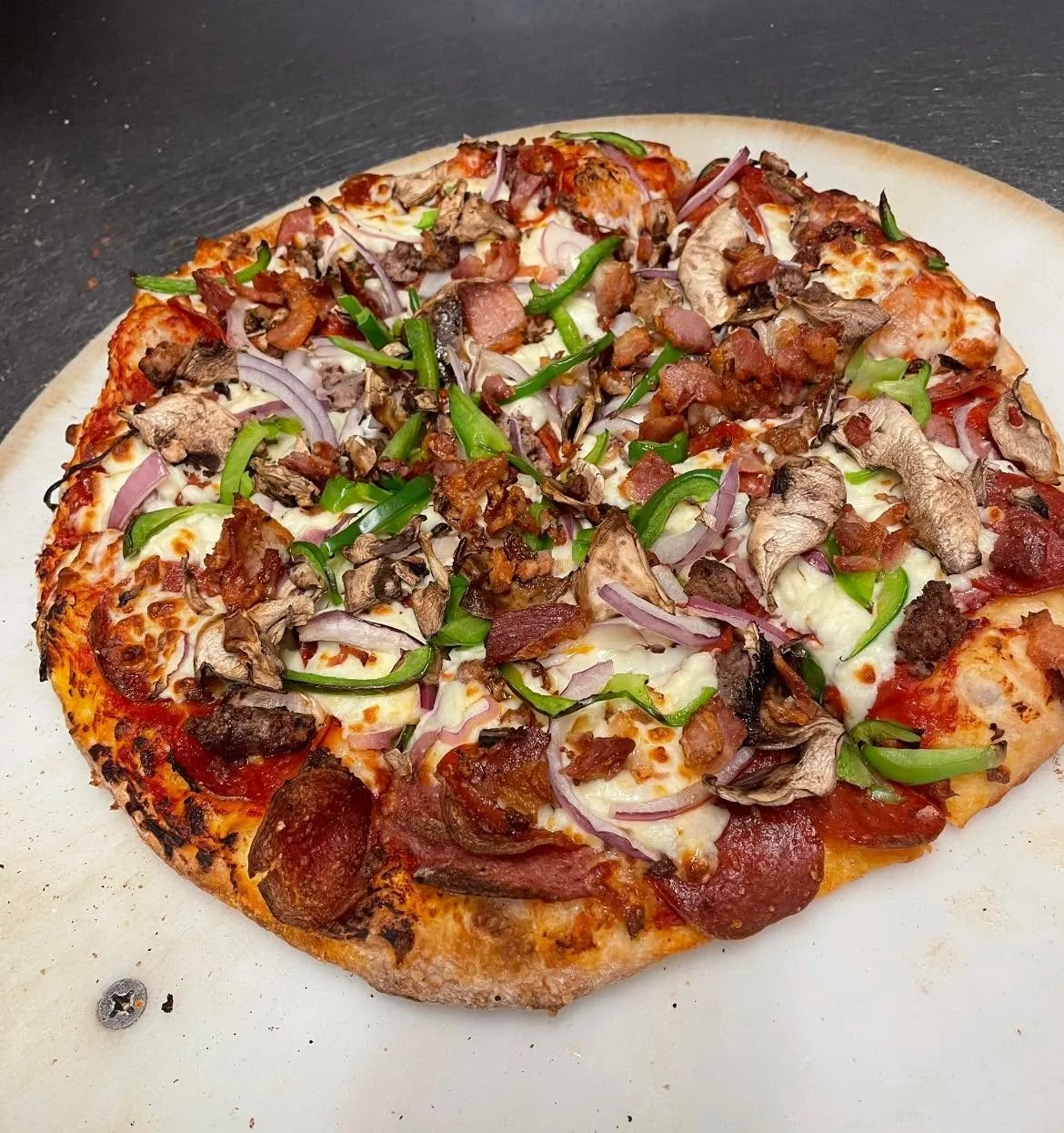 A supreme pizza with green pepper and red onion, seen from above