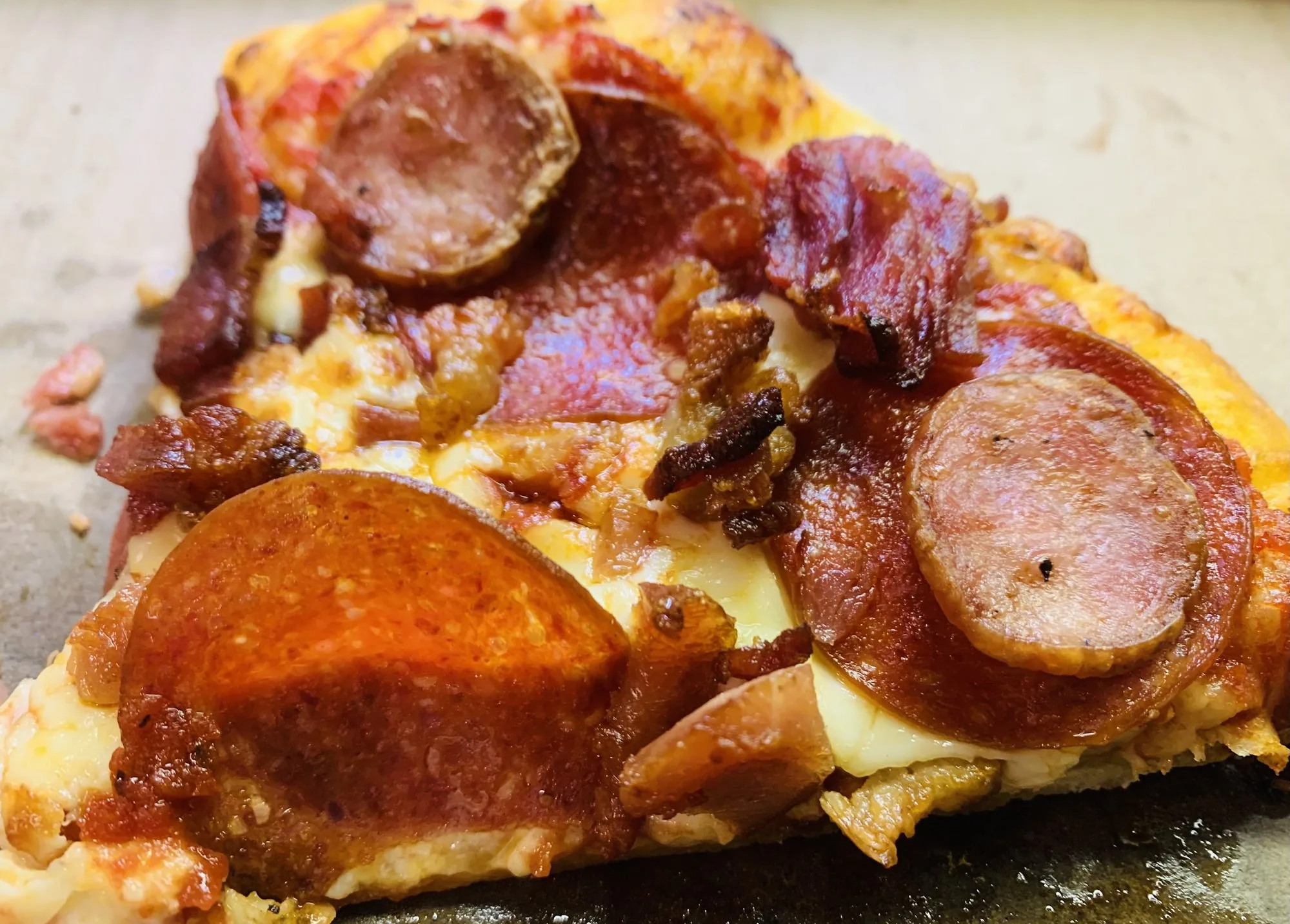Close-up of a meat slice with pepperoni, sausage and melted cheese
